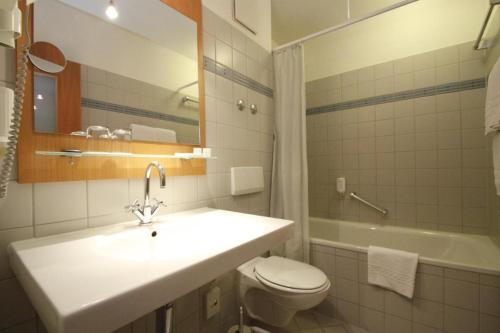 y baño con lavabo, aseo y bañera. en Hotel Havelland by PRIMA, en Götz
