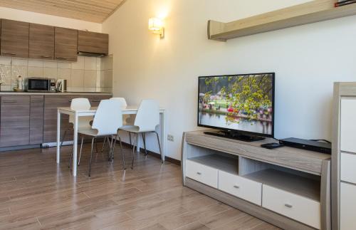 a living room with a television and a table with white chairs at Akva Apartement in Druskininkai