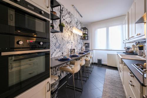 a kitchen with a long bar with stools in it at Lussuoso e accogliente appartamento con terrazza in San Donato Milanese