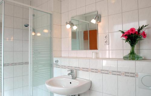 a bathroom with a sink and a vase with red flowers at Altstadthotel-Rheine in Rheine