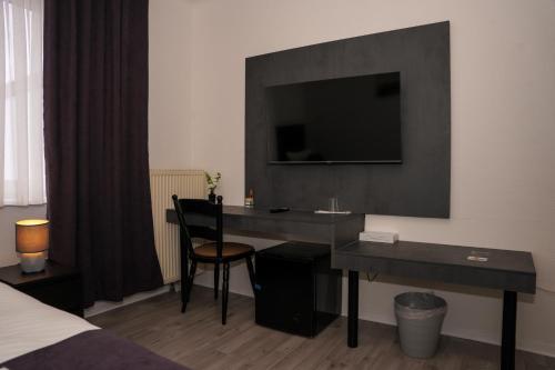 a hotel room with a desk with a television on the wall at GN Hotel Furpach in Neunkirchen