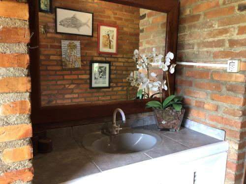 a bathroom sink with a mirror on a brick wall at Casa com Piscina e Acesso a Lagoa da Conceição NG0811 in Florianópolis