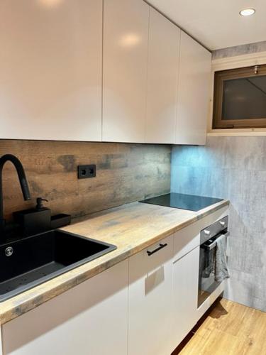 una cocina con armarios blancos y fregadero negro en Apartamento LOS CORZOS - LA PINILLA en Cerezo de Arriba