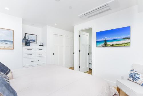 a white bedroom with a bed and a couch at BRAND NEW Luxury 1 Bedroom Condo Steps from the Beach in Newport Beach