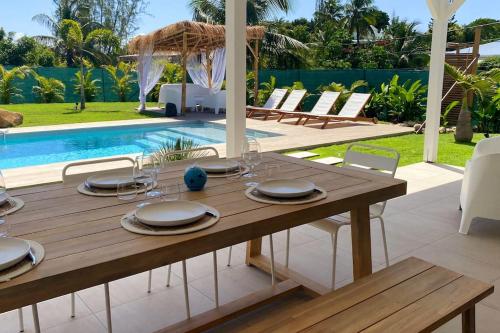 a wooden table with plates and napkins on it next to a pool at Villa du Levant-6/8 pers-Piscine in Saint-François