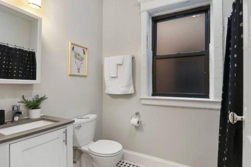 een witte badkamer met een toilet en een raam bij Well-Equipped 3BR Apartment with In-Unit Laundry - Bstone 2 in Chicago