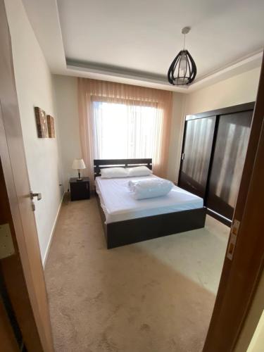 a bedroom with a large bed and a window at Modern Apart in Heart of Amman in Rujm ash Sharāʼirah