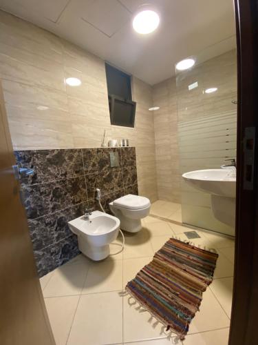 a bathroom with a toilet and a bidet and a sink at Modern Apart in Heart of Amman in Rujm ash Sharāʼirah