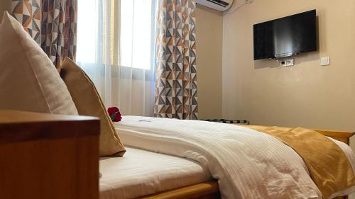 a room with a bed with a tv on the wall at JPN SQUARE Douala in Douala