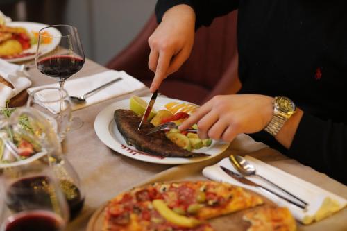 a person cutting a piece of fish on a table at Andoena Resort in Lipjan