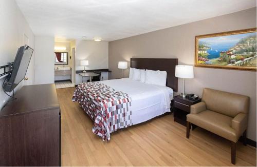 a hotel room with a bed and a chair at Red Roof Inn Lompoc in Lompoc