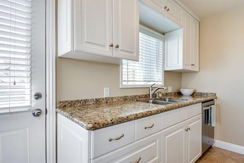 uma cozinha com armários brancos, um lavatório e uma janela em Beachfront Getaway on the Sand em Newport Beach