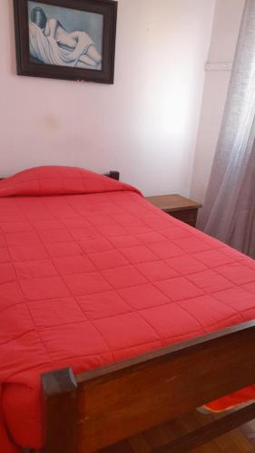 a bed with a red comforter in a bedroom at Hospedaje entre rokas in Huasco