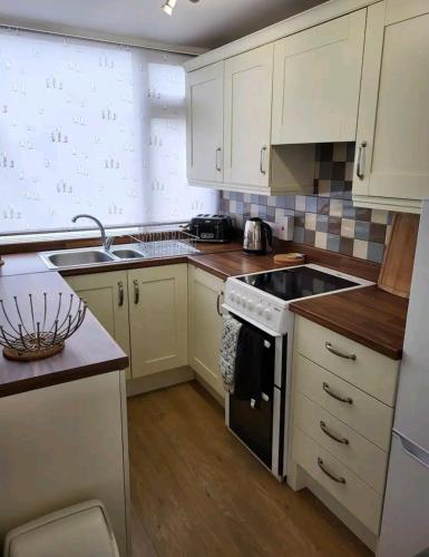 a kitchen with white cabinets and a stove top oven at The Salty Sea Dog - Dog friendly and 2 minutes walk to the beautiful, golden beach in Bridlington