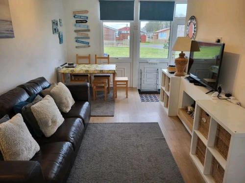 a living room with a leather couch and a table at The Salty Sea Dog - Dog friendly and 2 minutes walk to the beautiful, golden beach in Bridlington