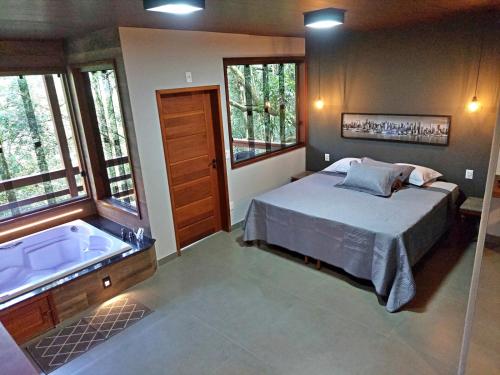 a bedroom with a bed and a bath tub at Pousada Aquarela - Macacos in Macacos
