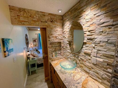 uma casa de banho com uma parede de pedra e um lavatório em Laguna Azul - Sleeps 8 + Heated Pool + Walk to Beach em St Pete Beach