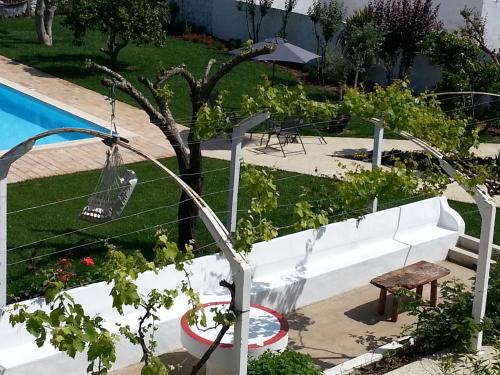 a garden with a tree and a swimming pool at Casas da Moagem in São Domingos