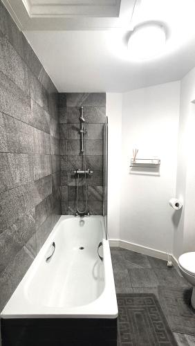 a bathroom with a bath tub and a toilet at Ideal for groups - Modern 2 Bedroom Apartment - Free Parking, Transit links, Close to Stadiums in Manchester