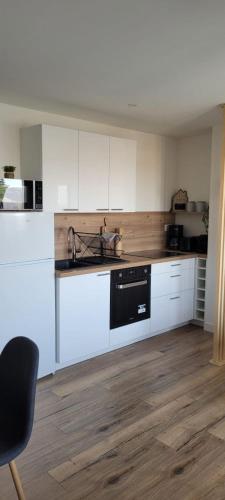 a kitchen with white cabinets and a black dishwasher at Studio neuf avec balcon et parking privé in Rochefort