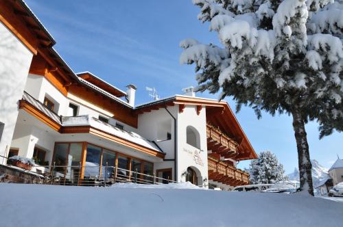 a house in the snow with a tree at Hotel Chalet Dlaces in Selva di Val Gardena
