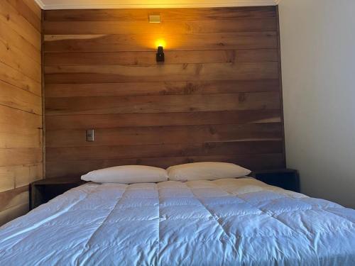 a bedroom with a bed with a wooden wall at Refugio Sereno in Puerto Octay
