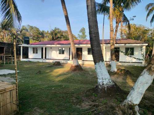 una casa con palmeras delante en Surjasto Resort, en Jaliapāra