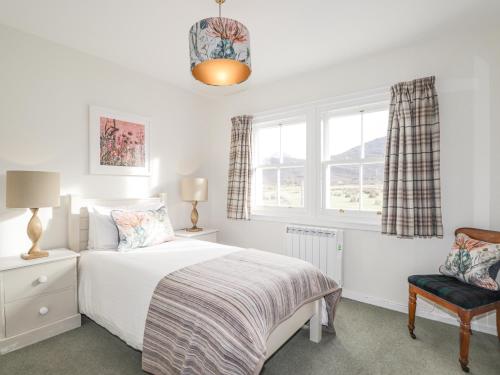 a bedroom with a bed and a chair and windows at Stalker's Cottage - Torridon in Achnasheen