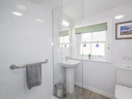 a white bathroom with a sink and a shower at Stalker's Cottage - Torridon in Achnasheen