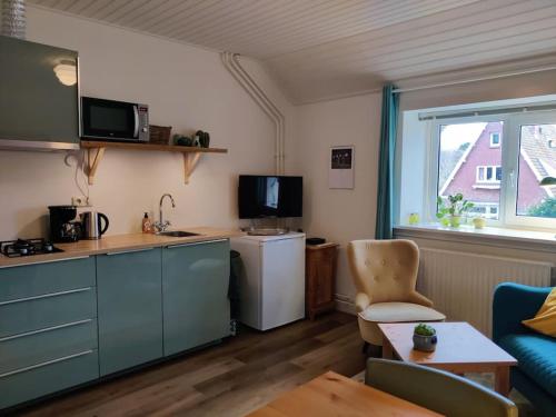 een keuken en een woonkamer met een koelkast en een tafel bij In het Centrum in Bergen