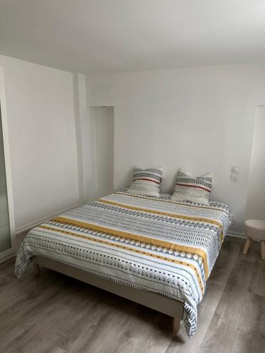 a bed in a room with white walls and wooden floors at Le cocon Ruellois in Rueil-Malmaison