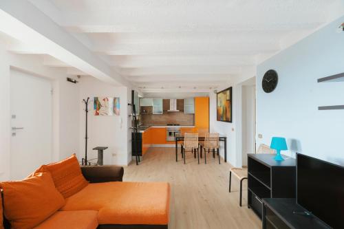 a living room with an orange couch and a dining room at Beach Appartament in Marina di Montemarciano