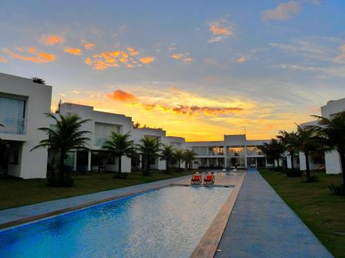 a swimming pool with two chairs in front of a building at B Blue Beachouses in Itacimirim