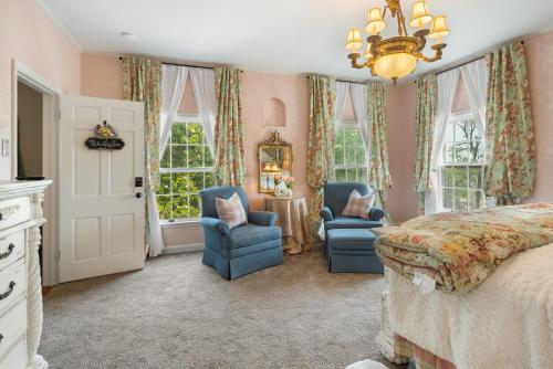 um quarto com 2 cadeiras, uma cama e janelas em Grand Mansion-Blushing Rose em Fort Smith