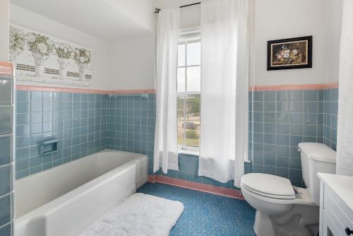 baño de azulejos azules con bañera y aseo en Grand Mansion-Blushing Rose en Fort Smith