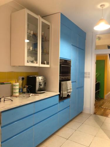 een keuken met blauwe kasten en een magnetron bij Rosie Blue in Londen