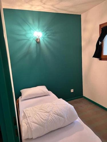- une chambre dotée d'un lit avec un mur vert dans l'établissement Appartement avec grand extérieur, à Saint-Lary-Soulan