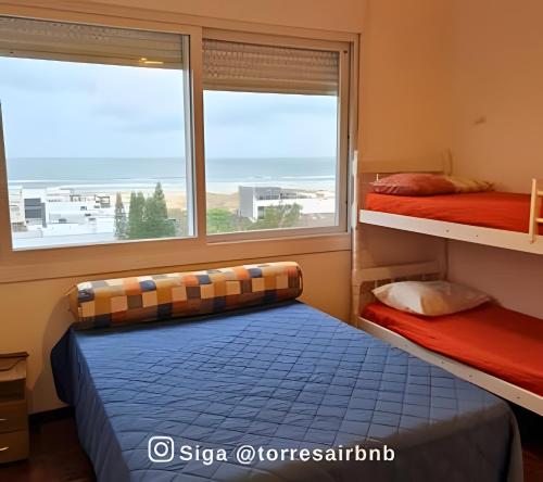 a bedroom with two bunk beds and a window at Apartamento com vista para o mar in Torres