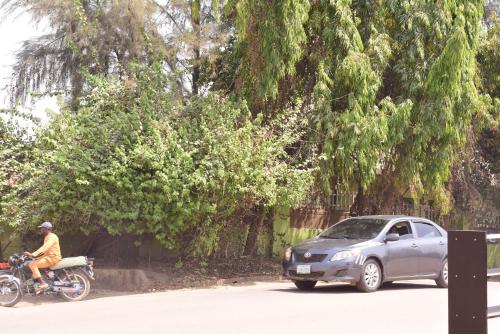 a man riding a motorcycle next to a car at Royal Suites And Apartments Lugbe, Abuja 