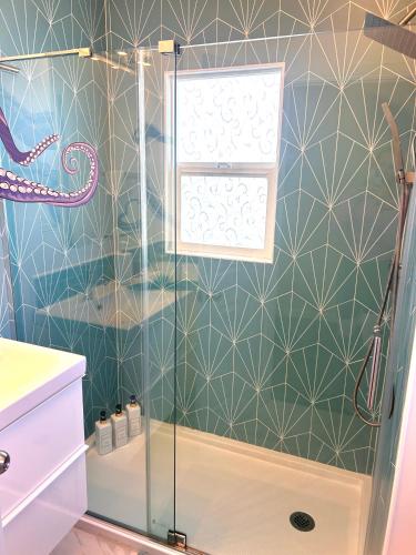 a shower with a glass door in a bathroom at Casa California - Backyard, BBQ, Firepit & Near Beaches in San Diego
