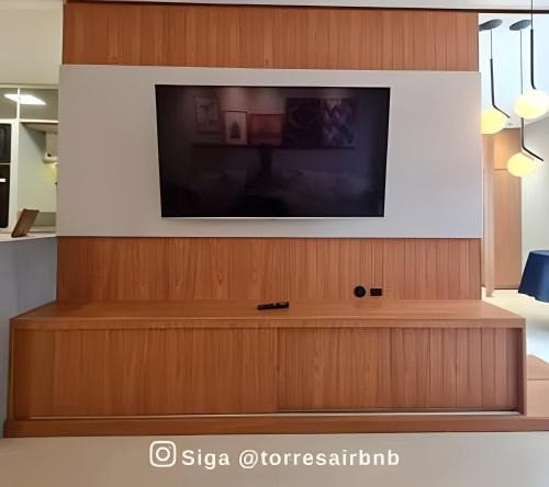 a flat screen tv on a wooden wall at Apto 02 quartos | Ar | 500mts do mar | Aceita Pet in Torres