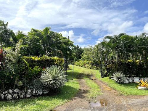 una puerta en un jardín con plantas y árboles en Fale Mailani-2 rooms/AC/hotwater, en Vaitele