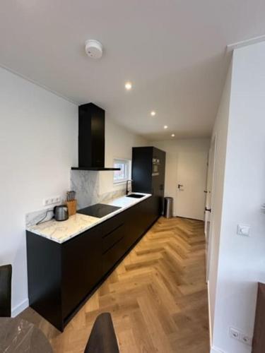 a kitchen with black cabinets and a wooden floor at Luxe boshuisje Arlo in Ermelo! in Ermelo