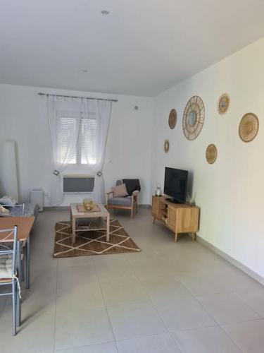 un salon blanc avec une table et une télévision dans l'établissement 2 pièces rez-de-chaussée Mandelieu, à Mandelieu-la-Napoule