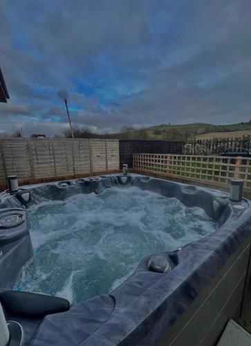 a large jacuzzi tub with water in it at The Birch Lodge located in Pegsdon in Hexton