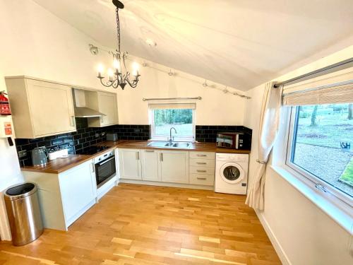 eine Küche mit weißen Schränken, einem Waschbecken und einem Fenster in der Unterkunft The Applewood Lodge in Heytesbury