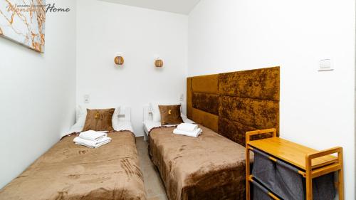 Cette chambre comprend 2 lits et une table en bois. dans l'établissement Wonder Home - Apartament Enya blisko deptaka, miejskiego placu zabaw i Parku Zdrojowego, à Świeradów-Zdrój