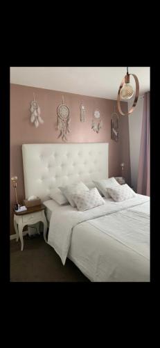 sypialnia z dużym białym łóżkiem z zagłówkiem w obiekcie Appartement 4 personnes idéal JO 2024 w mieście Tremblay-en-France