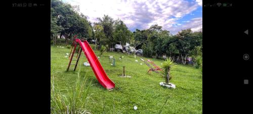 a playground with a red slide in a field at Chácara Boa Esperança in Franco da Rocha