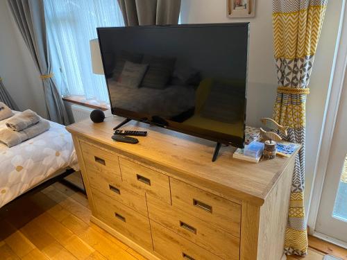 a flat screen tv on a wooden dresser in a bedroom at THE STUDIO PORTHYRAUR in Criccieth